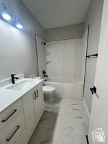 Modern bathroom featuring a white vanity with integrated sink, matte black faucet, and bronze hardware