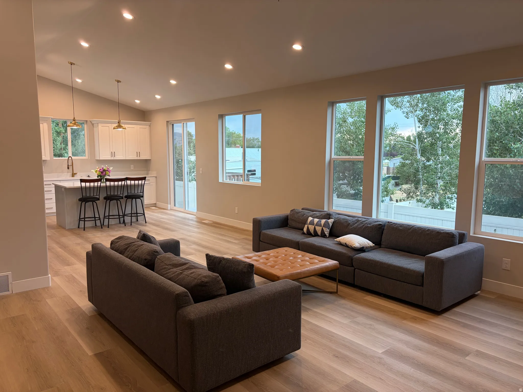 Open-concept living area featuring wood-finish flooring, recessed lighting, and large windows