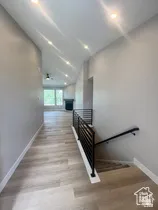 Hallway featuring wood-finish flooring, recessed lighting, and a modern horizontal bar railing