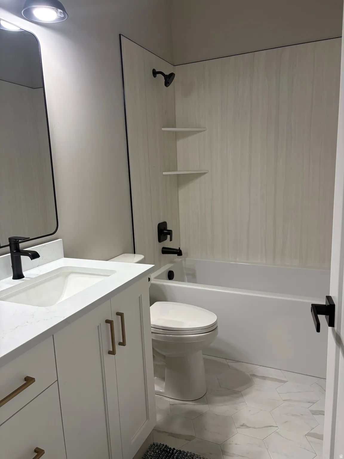 Bathroom featuring a white vanity with gold-tone hardware, a white countertop with an integrated sink, and matte black plumbing fixtures