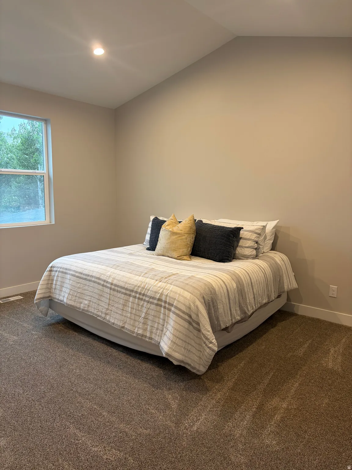 Vaulted ceiling bedroom featuring plush carpeting, a recessed ceiling light, and a white-framed window