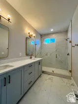 Bathroom featuring a dual vanity with light blue cabinetry, white countertops, and bronze hardware
