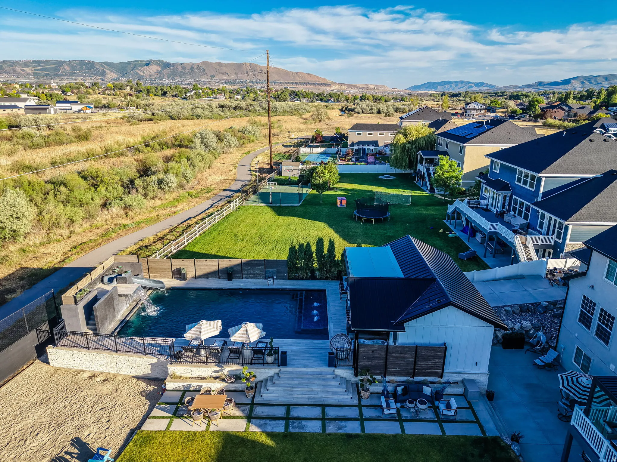Expansive backyard featuring a rectangular swimming pool with a slide, surrounding patio space, and a dedicated pool house