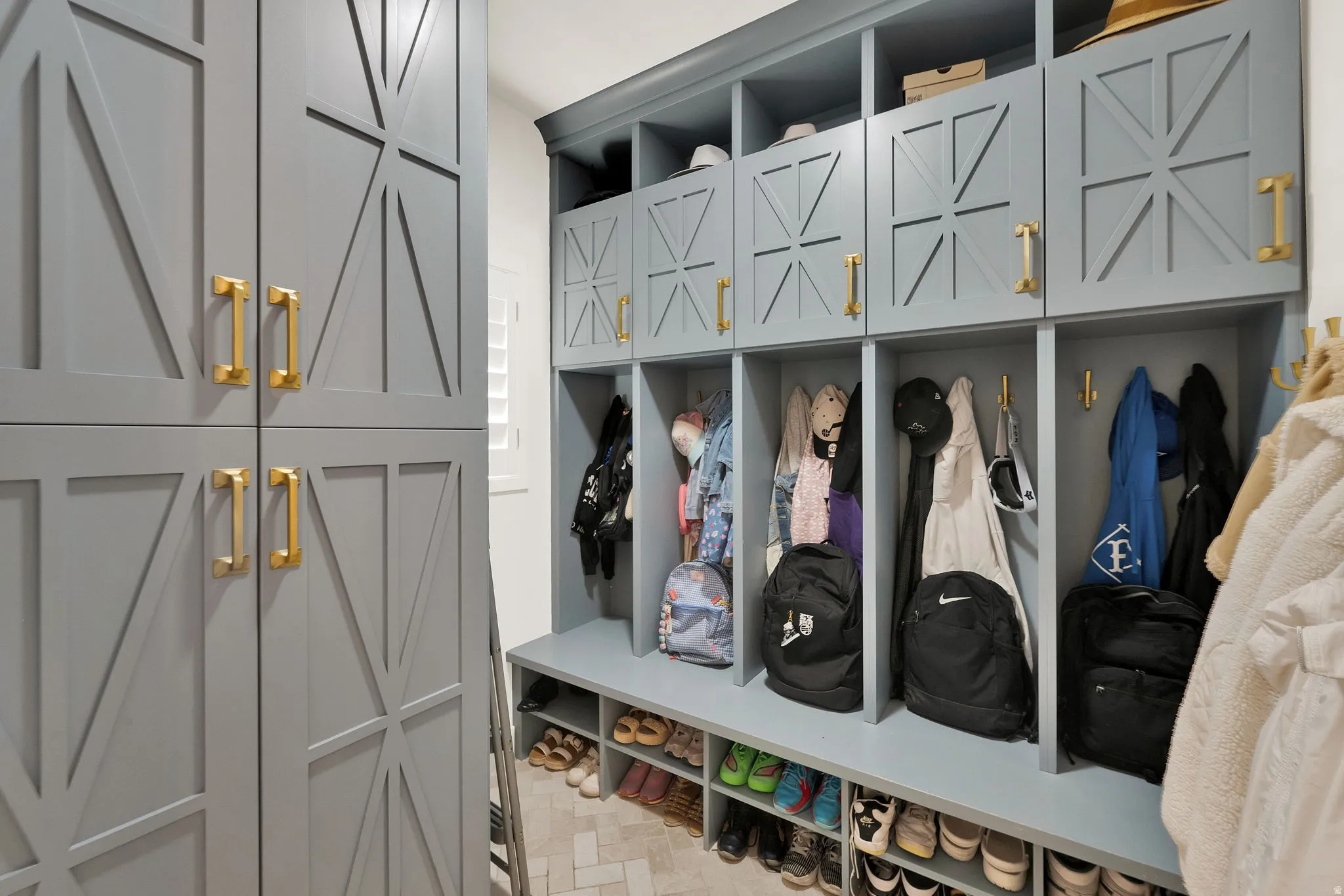 Custom built-in mudroom cabinetry with a light blue finish and gold-tone hardware