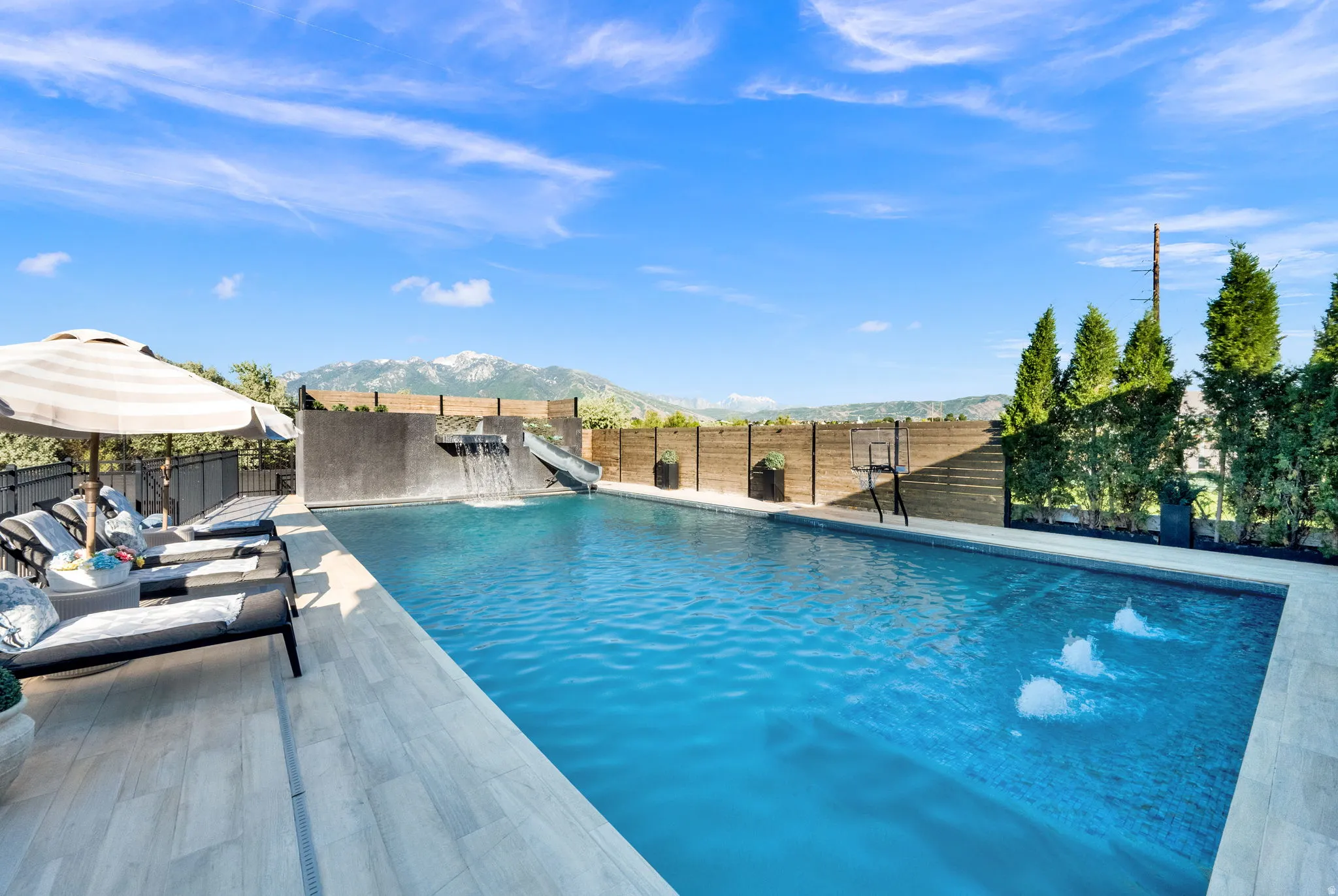 Expansive outdoor pool area featuring a water slide, a built-in waterfall, and multiple water spouts