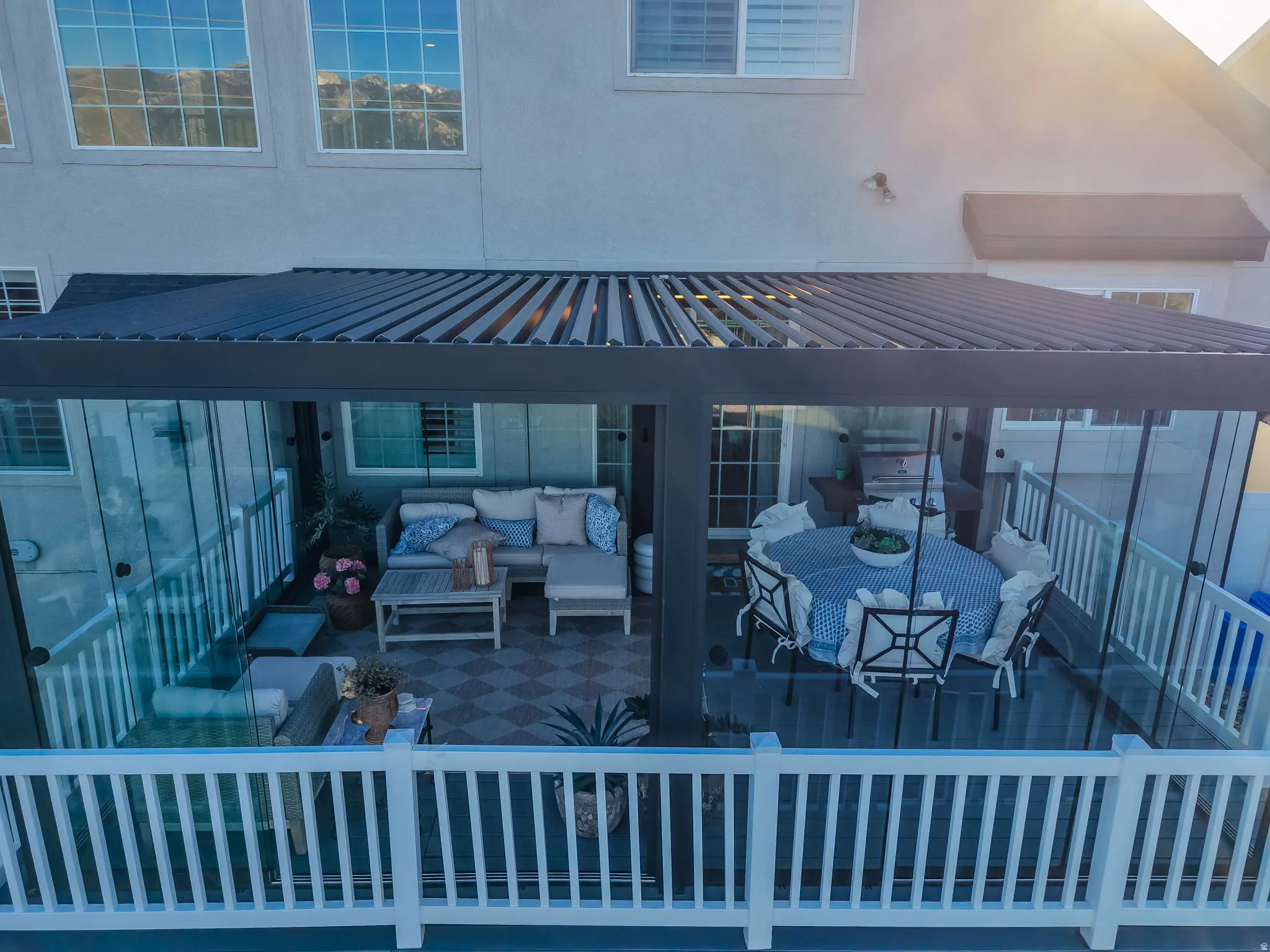Covered outdoor living space featuring a louvered pergola roof and glass panel enclosures