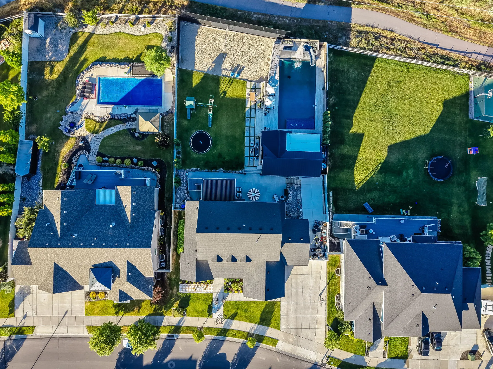 Expansive private yard featuring two distinct swimming pools, extensive patio areas, manicured lawns, and mature landscaping