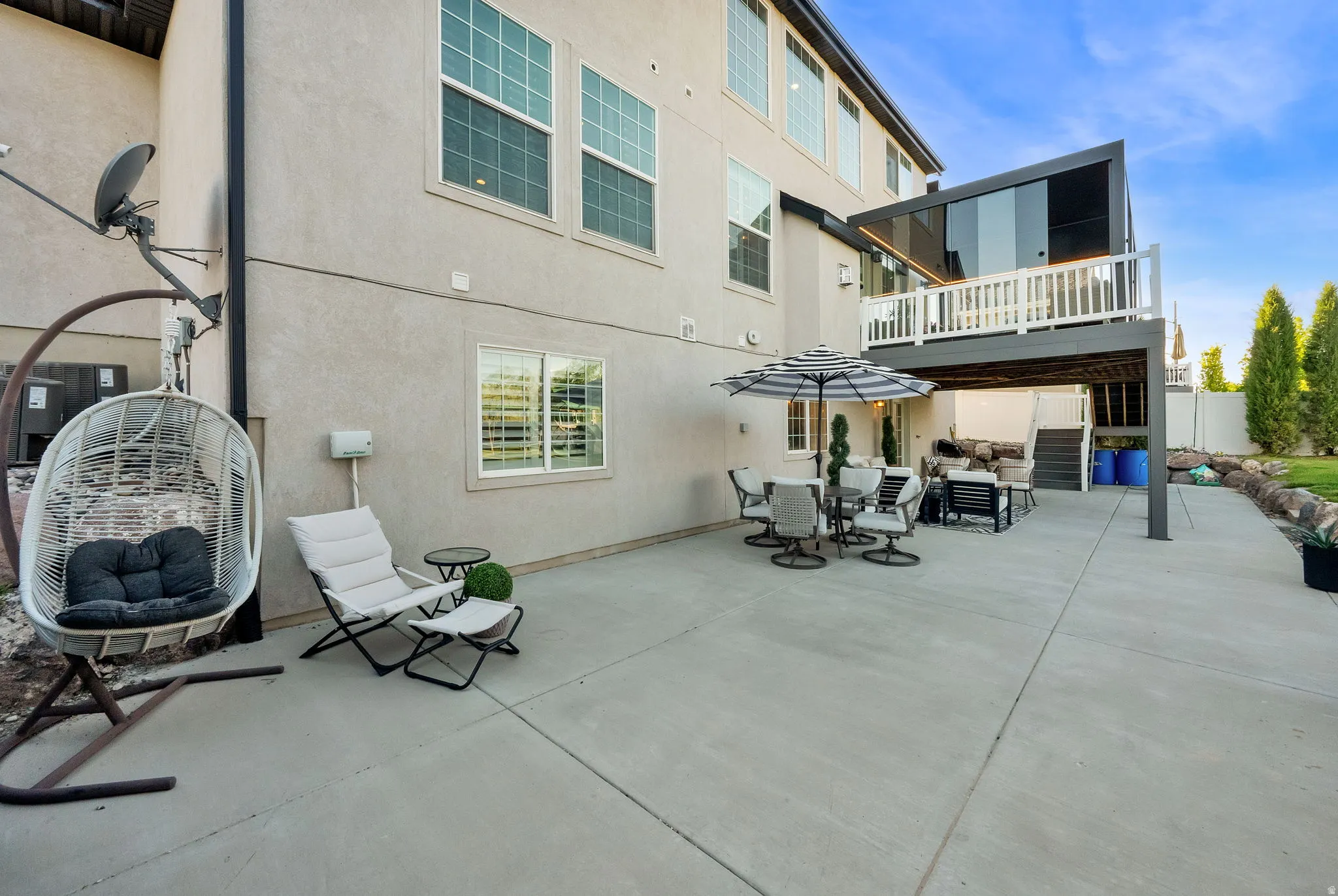 Expansive concrete patio with a full-width upper deck featuring a glass enclosure