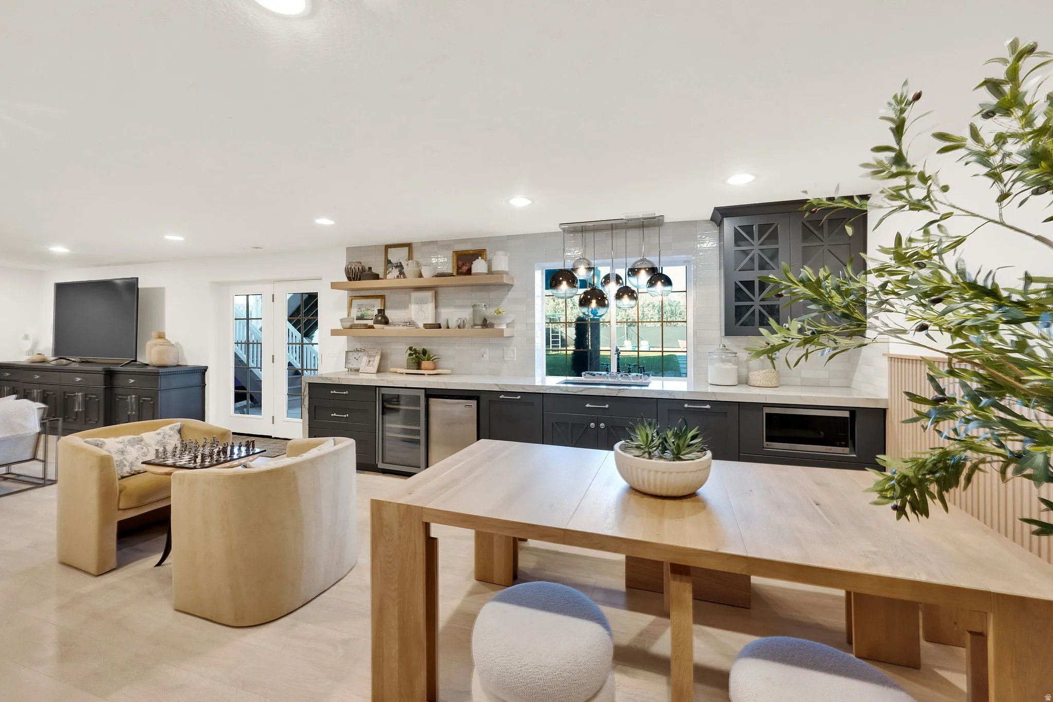 Entertainment room featuring recessed lighting, light wood-finish flooring, a built-in wet bar with dark cabinetry, integrated beverage refrigeration, and a tile backsplash