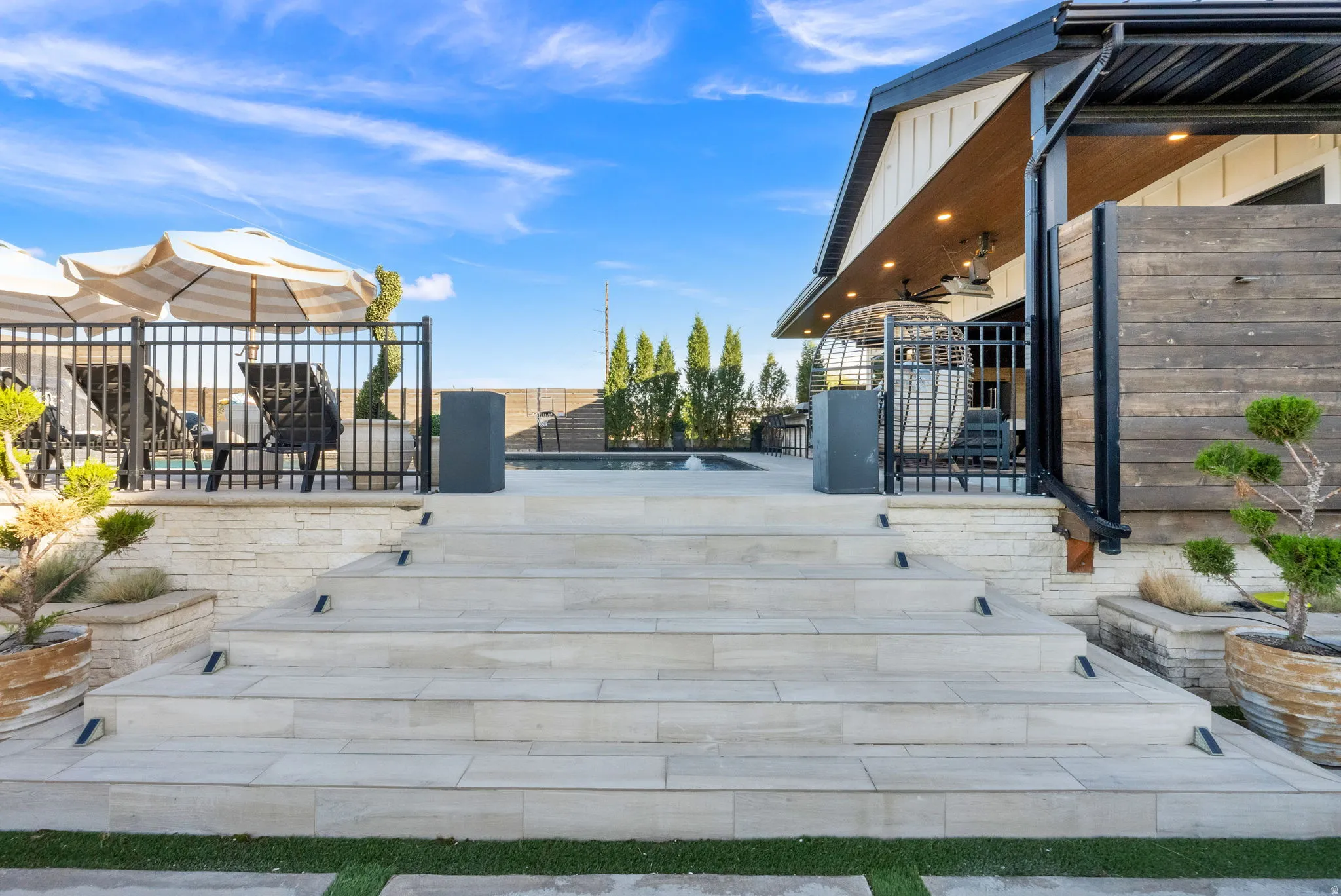 Tiered patio steps crafted from light-toned pavers ascend to an outdoor living area