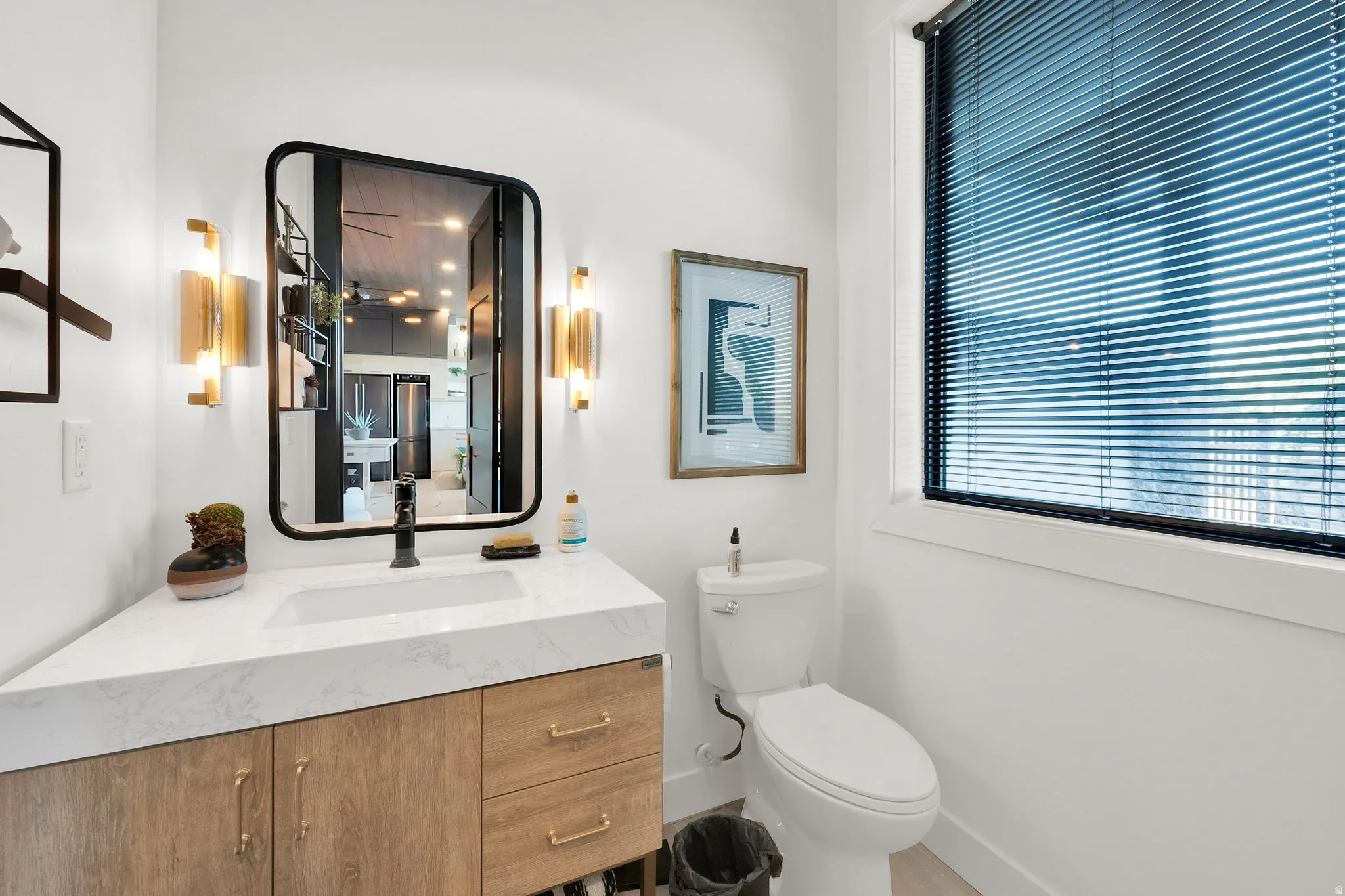 Contemporary vanity with a white countertop and natural wood-finish cabinetry, featuring a rectangular basin and matte black faucet