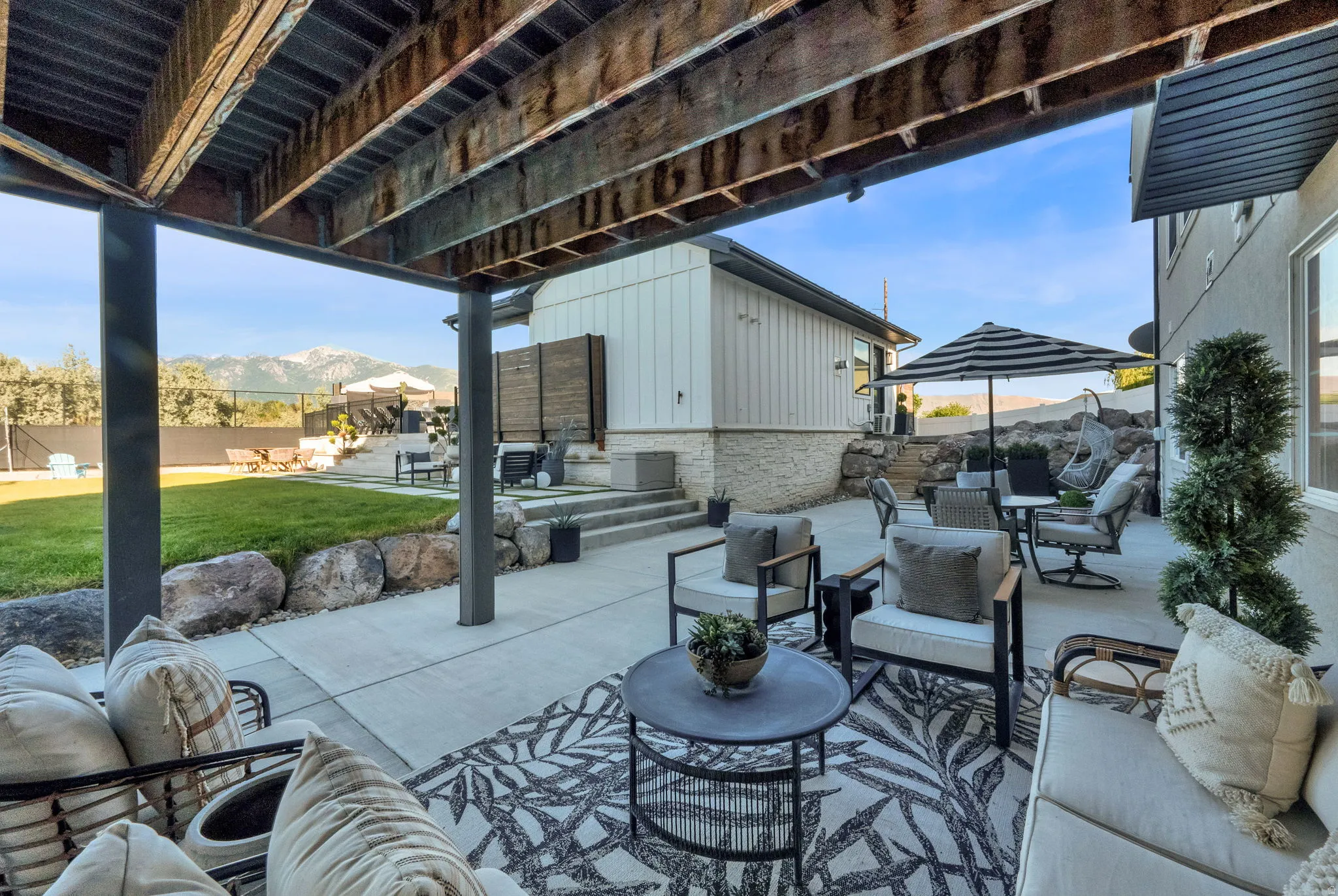 Expansive concrete patio under an elevated deck featuring a large decorative area rug
