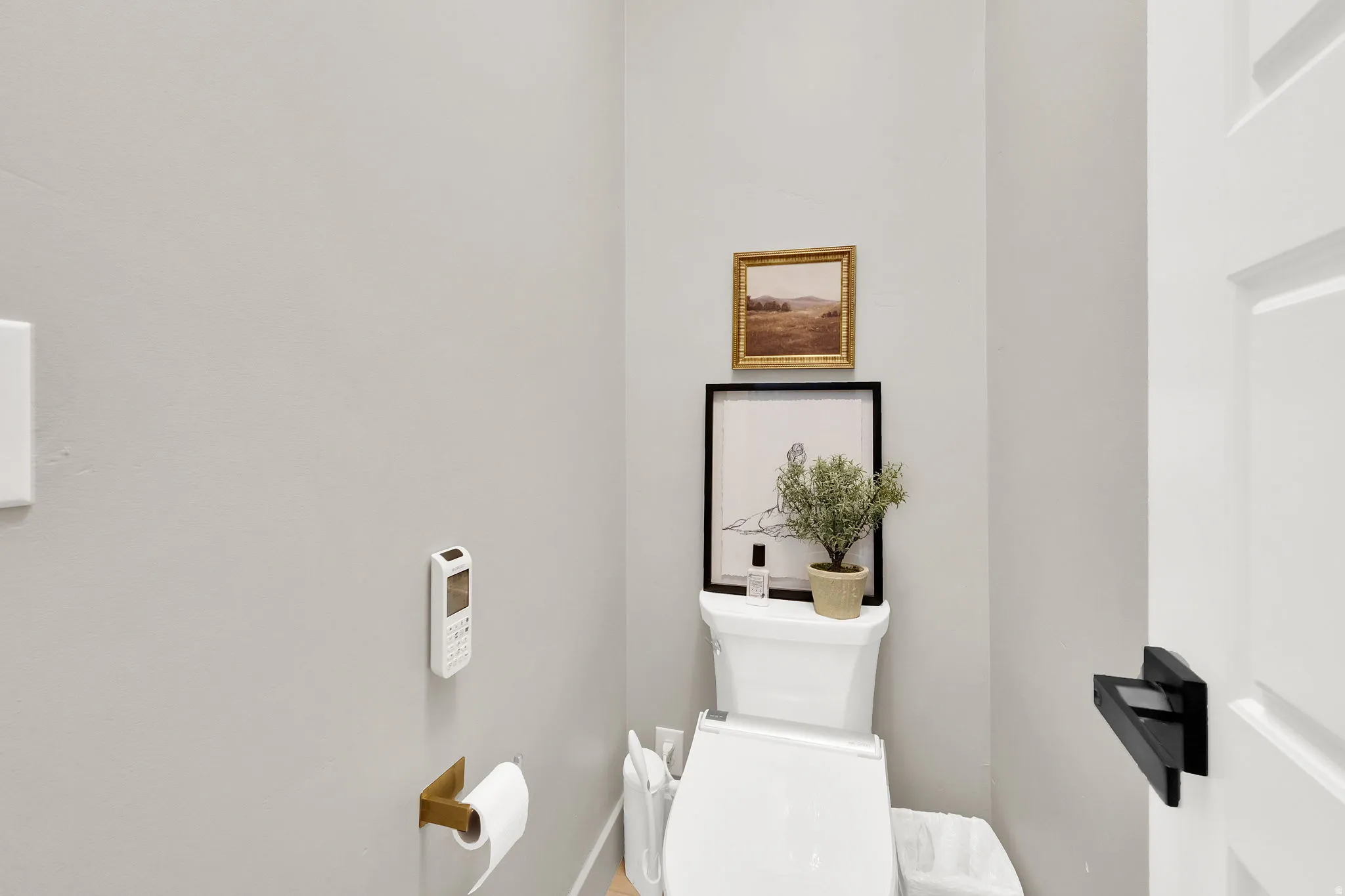 Compact water closet featuring light gray walls and a white toilet