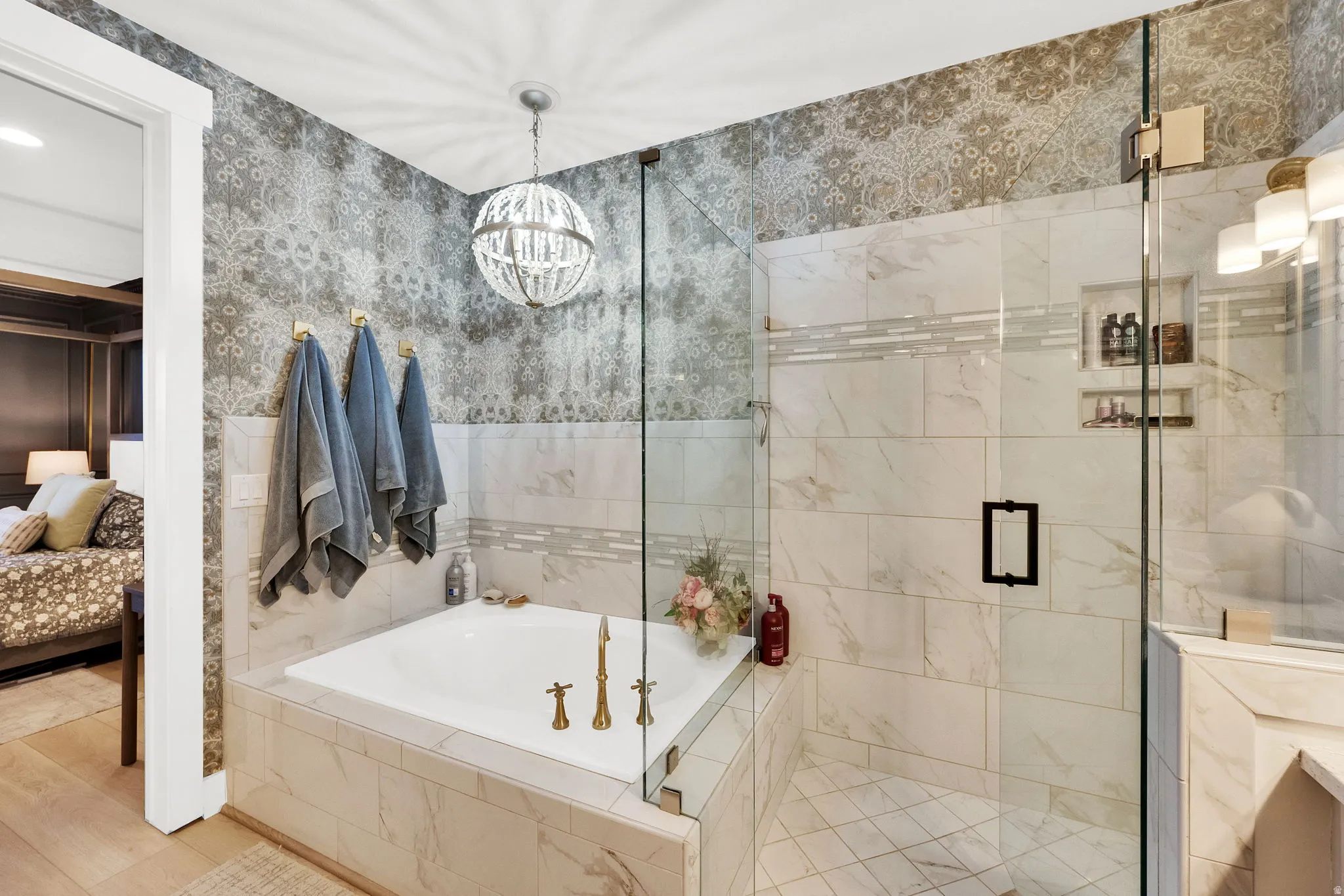 Spa-inspired bathroom featuring a built-in tub with brass fixtures, a glass-enclosed shower with a tiled bench and recessed shelving, and decorative wall tiling