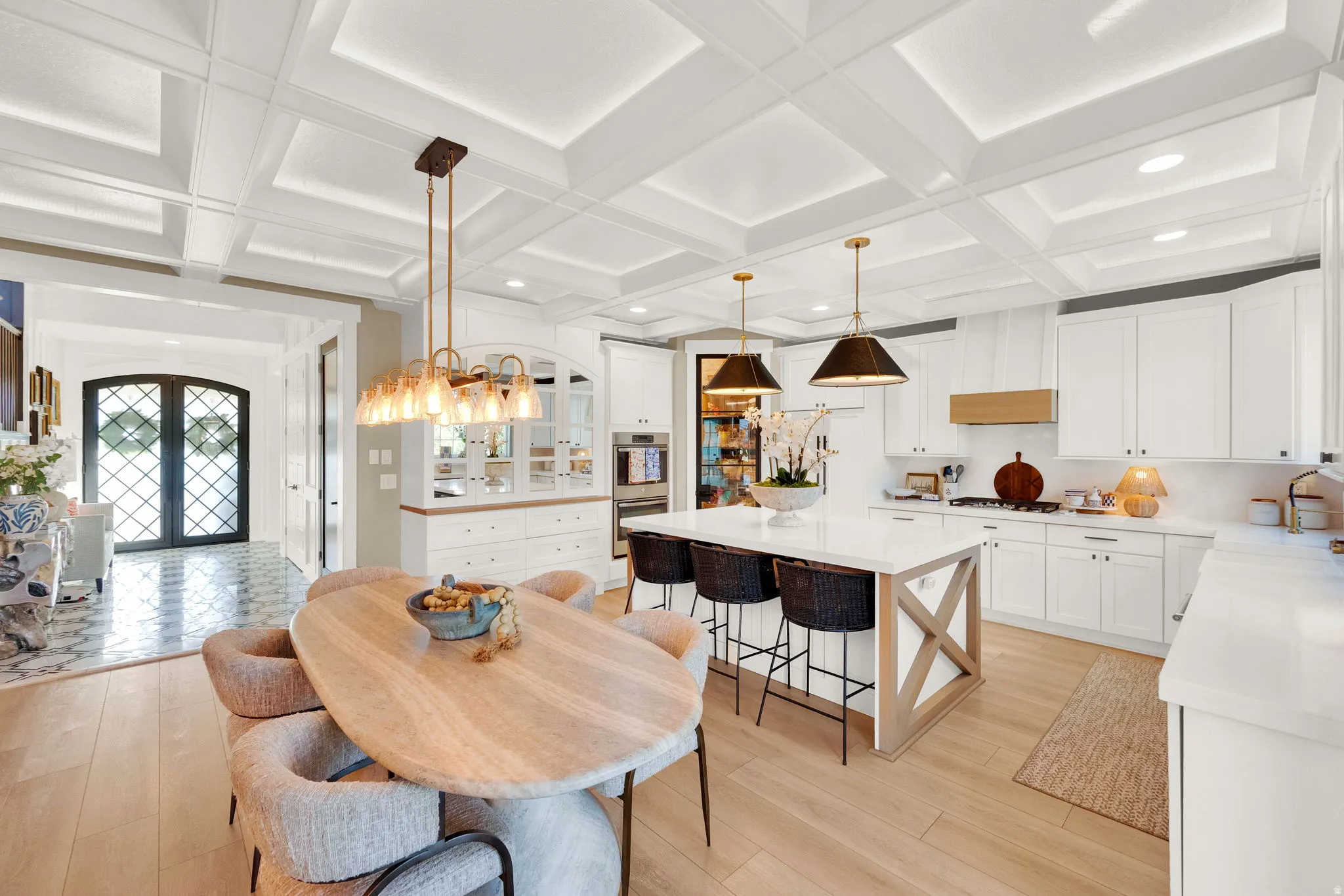 Gourmet kitchen featuring a substantial island with seating, integrated appliances, white cabinetry, and wood-finish flooring