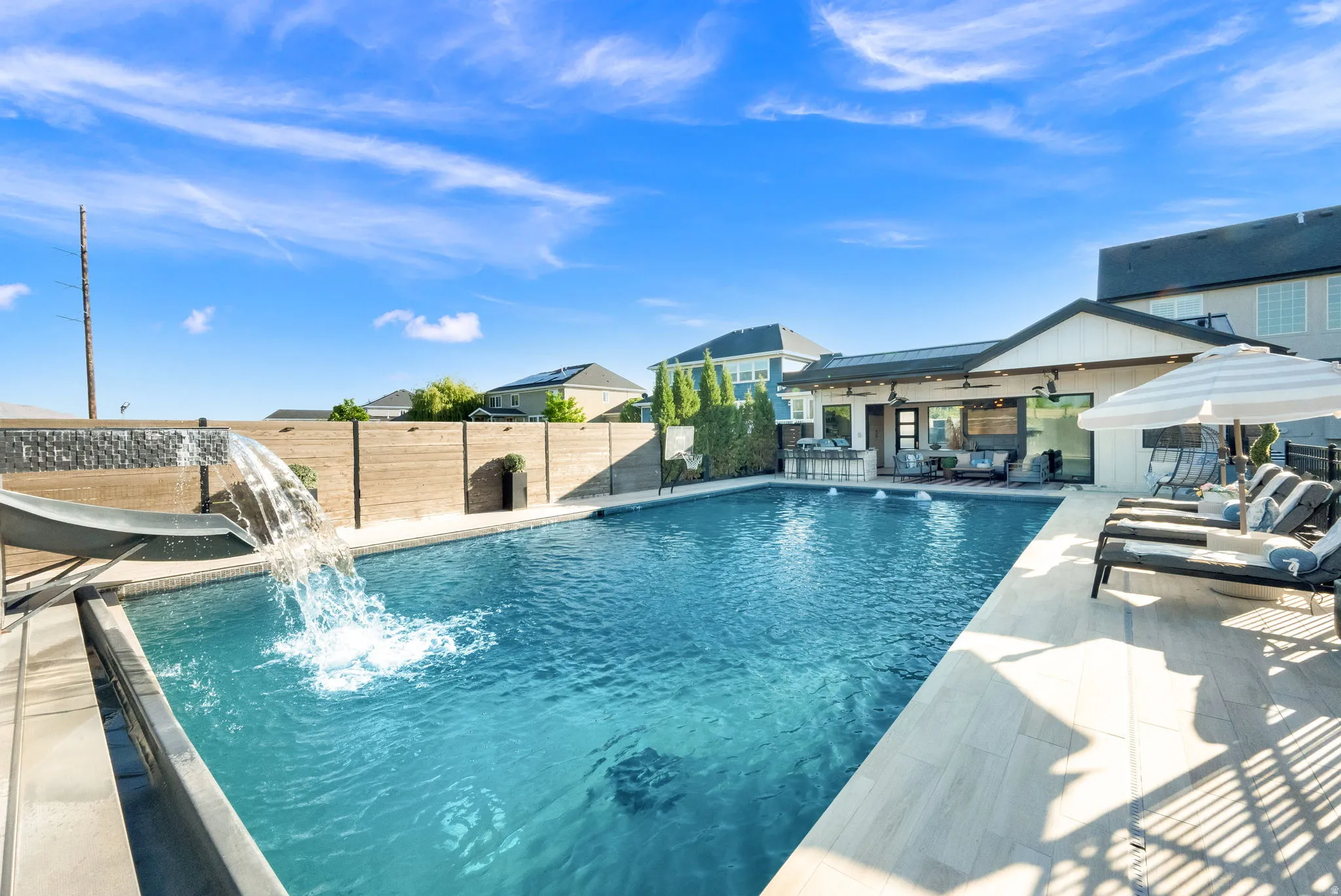 Expansive swimming pool featuring a waterfall and integrated slide