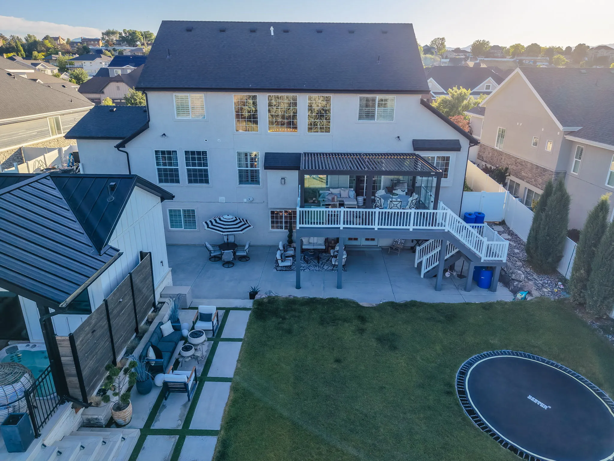Spacious backyard featuring a multi-level deck with a pergola, a concrete patio, a dedicated lawn area, and a detached structure with a metal roof