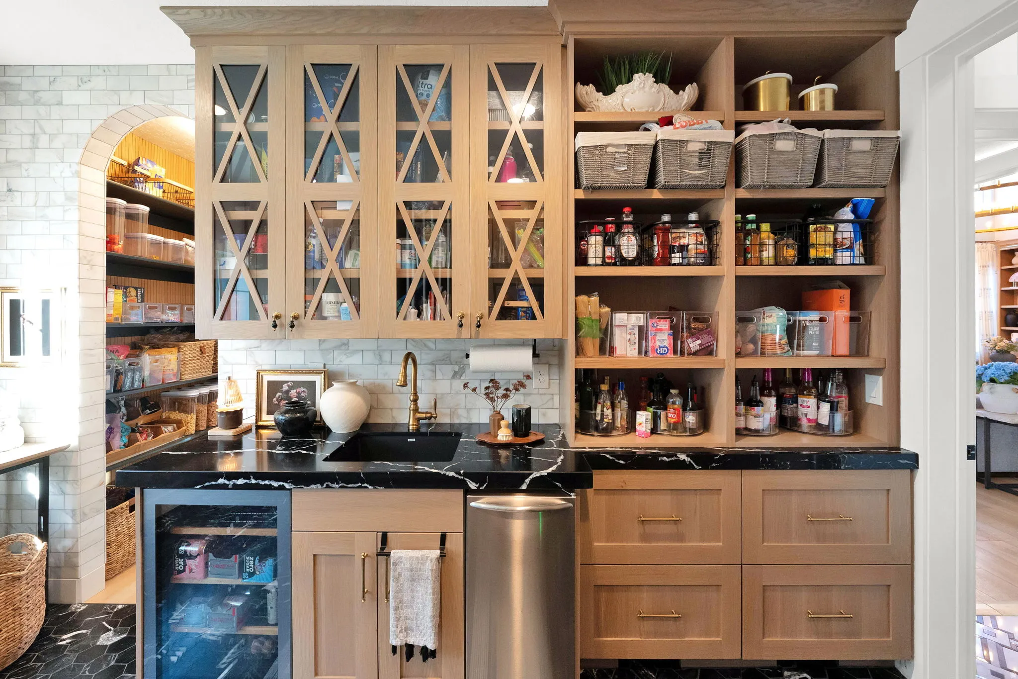 Custom pantry with light wood cabinetry, black countertops, and black tile flooring