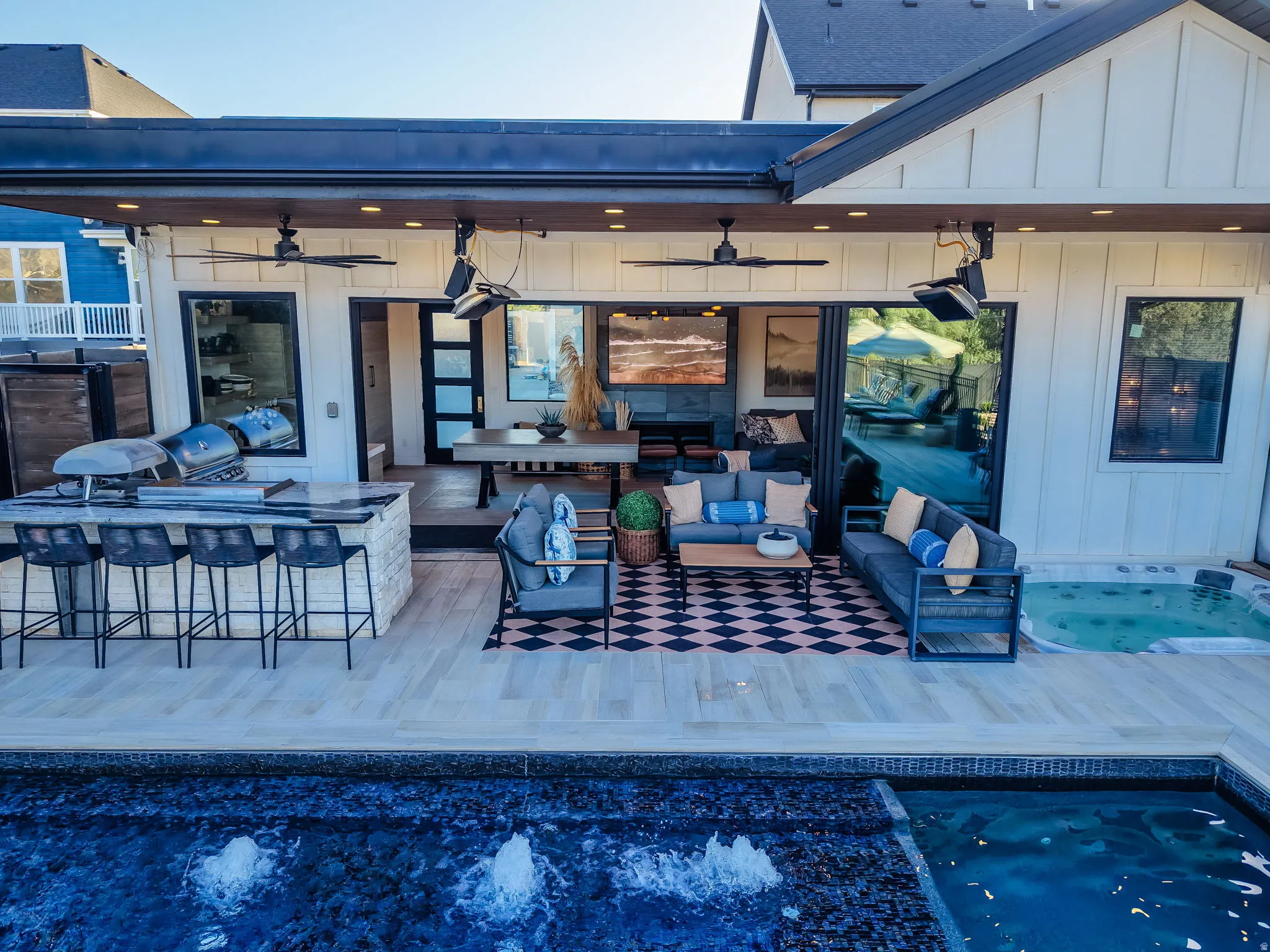 Expansive outdoor living area featuring a covered patio with recessed lighting and ceiling fans