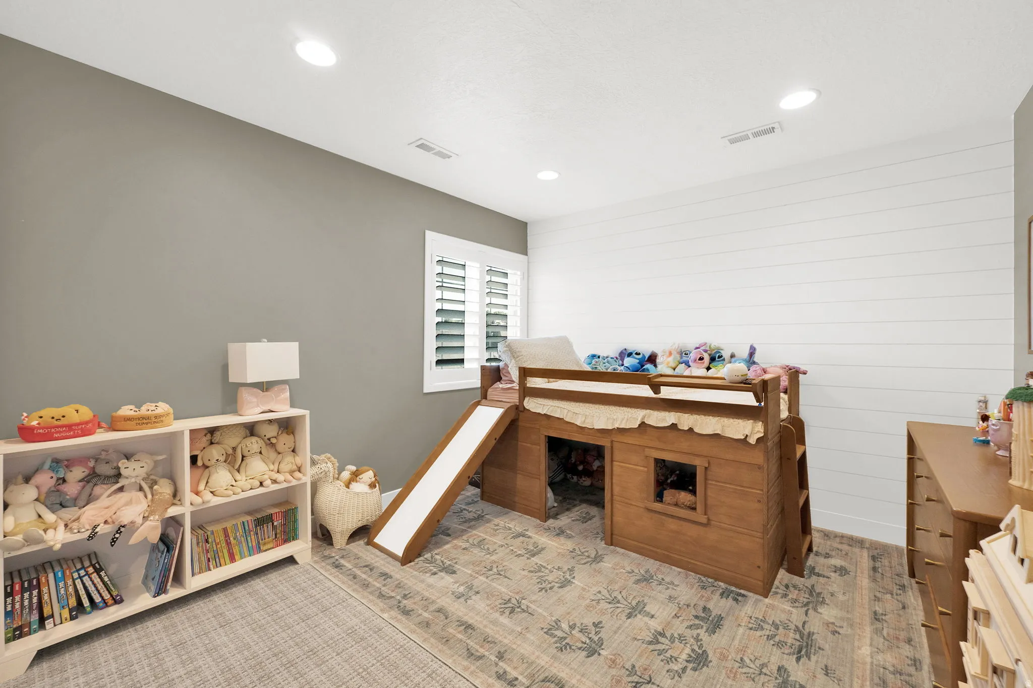 Bedroom featuring recessed lighting, a window with white plantation shutters, and a shiplap accent wall