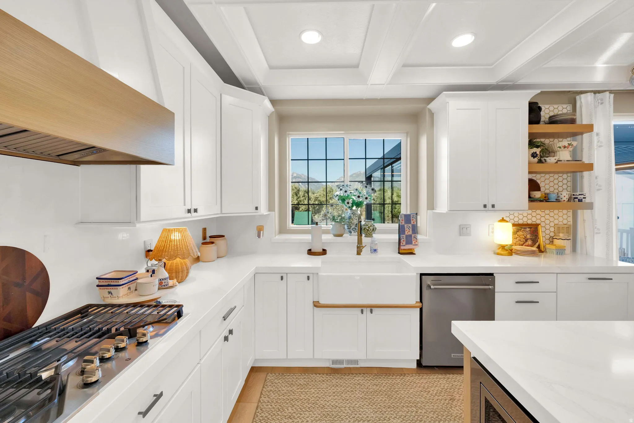 U-shaped kitchen featuring white cabinetry, a farmhouse sink, stainless steel appliances, and a coffered ceiling