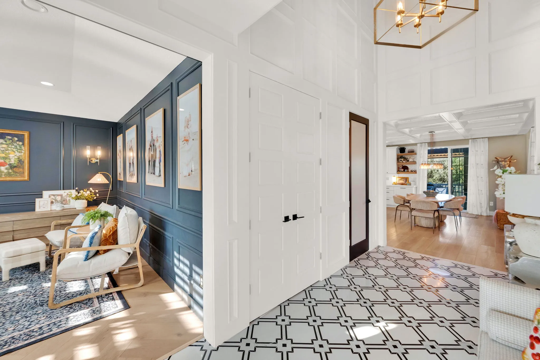 Entryway featuring geometric patterned floor tiles, white wainscoting, and a brass geometric chandelier