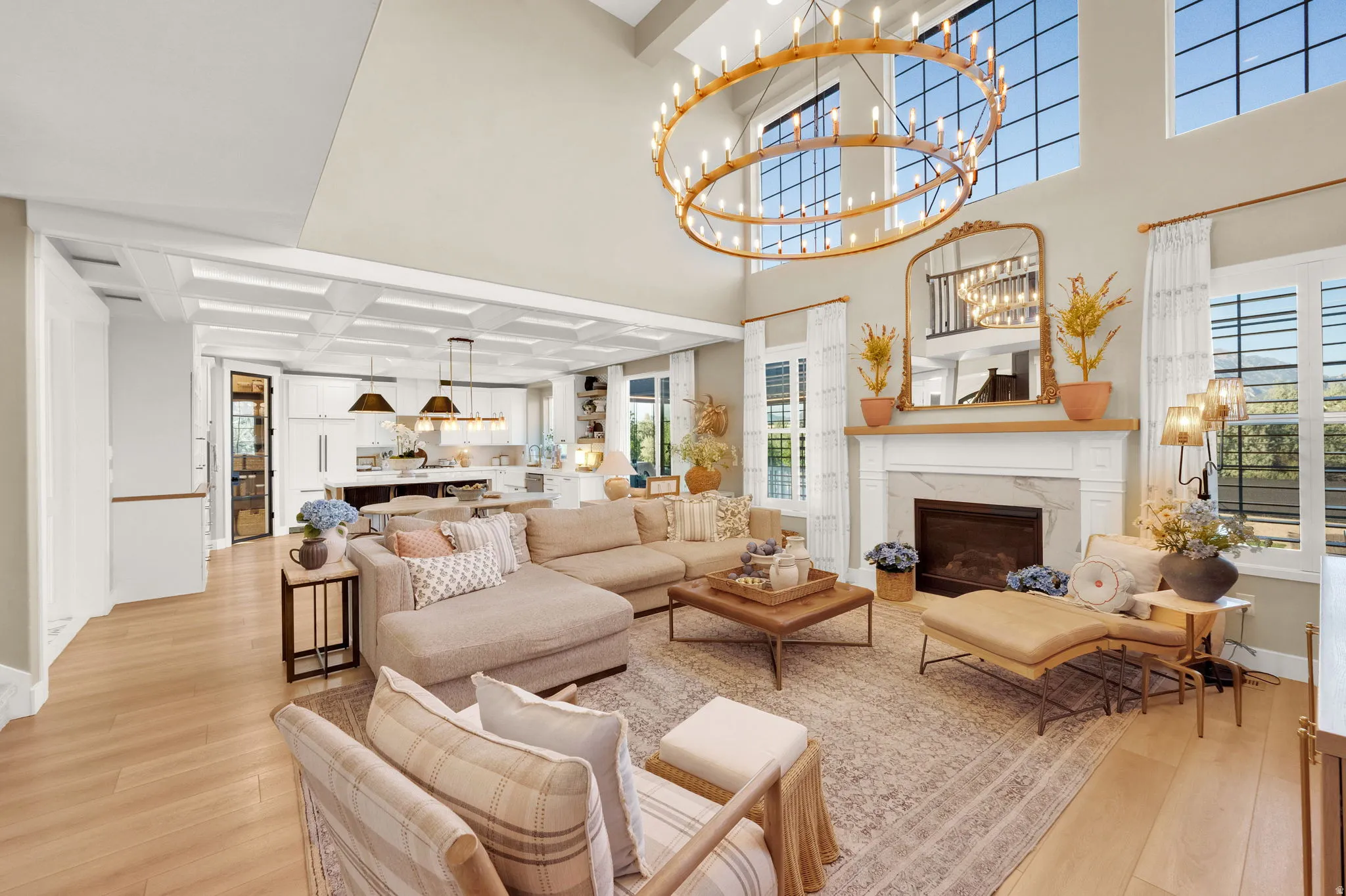 Great room featuring a vaulted ceiling with a large circular chandelier, multiple tall windows, and light wood-finish flooring