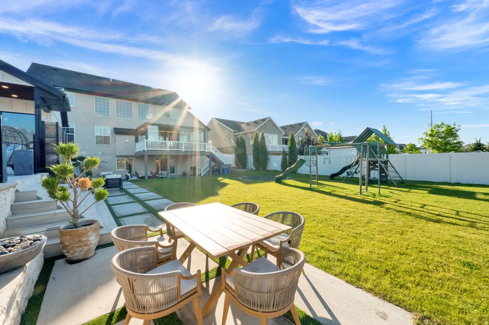 Expansive backyard featuring a lush lawn, concrete patio, and a dedicated play structure