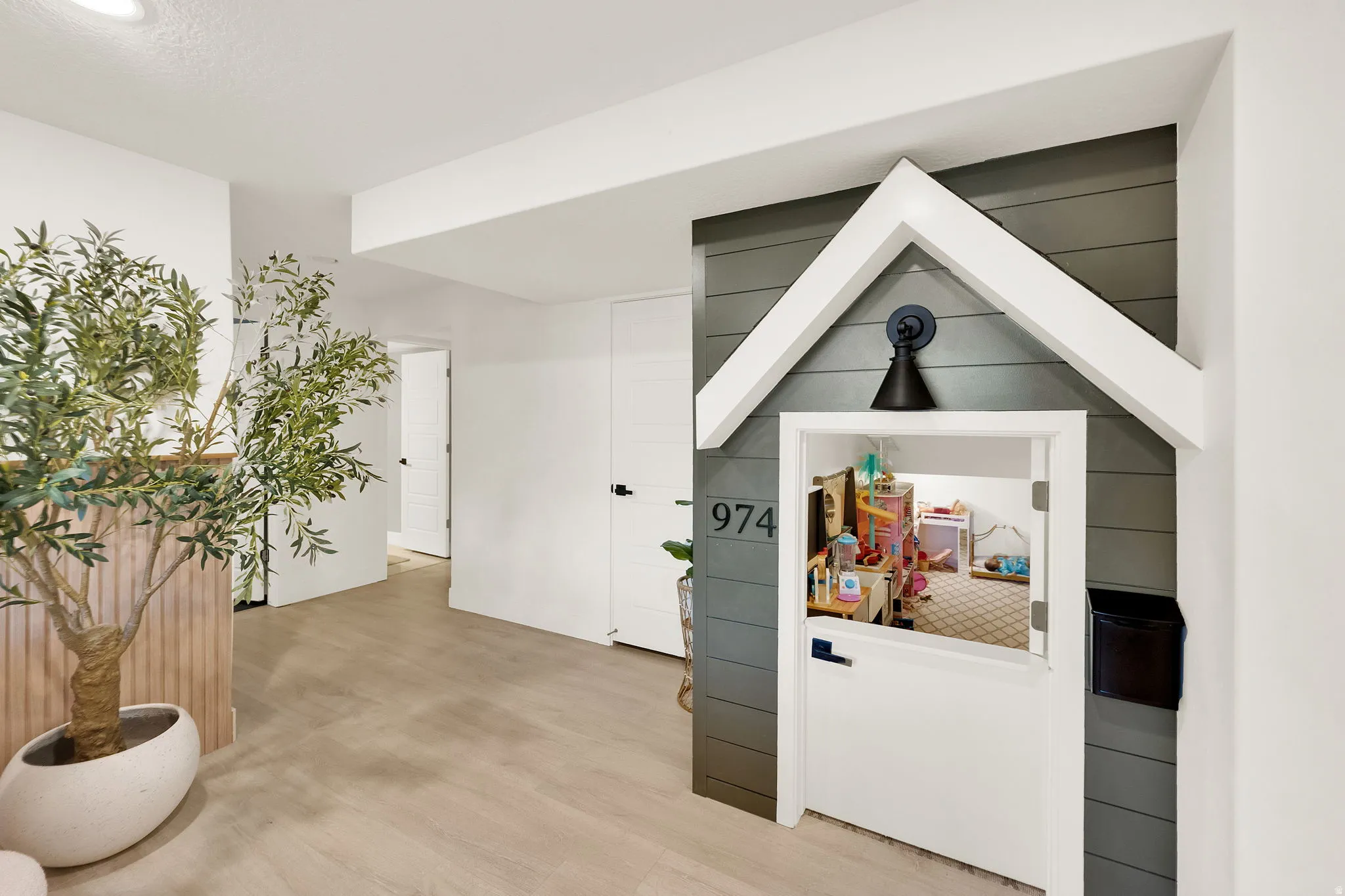 Custom built-in structure featuring a miniature house design with a functional door, decorative house numbers, and an overhead light fixture