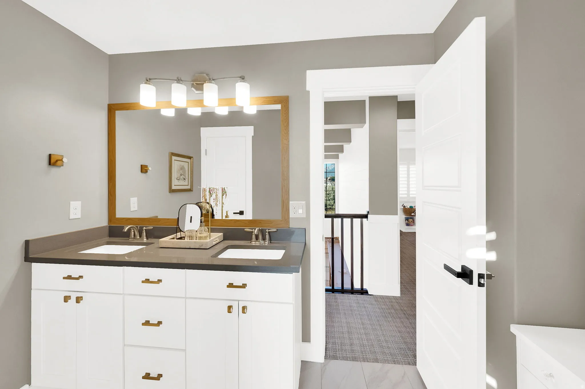 Bathroom vanity featuring dual undermount sinks, bronze faucets, and a dark stone-finish countertop