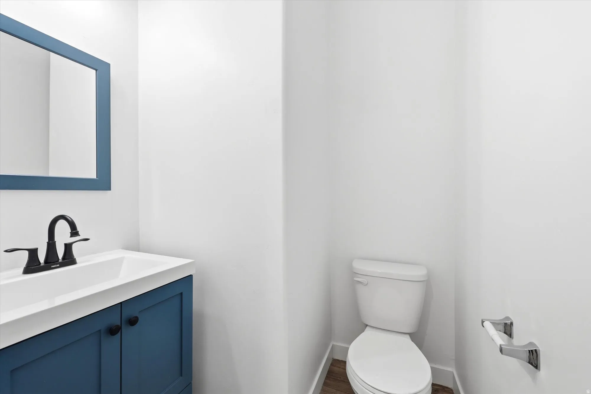 Bathroom featuring a blue vanity with an integrated sink, matte black faucet, and coordinating framed mirror