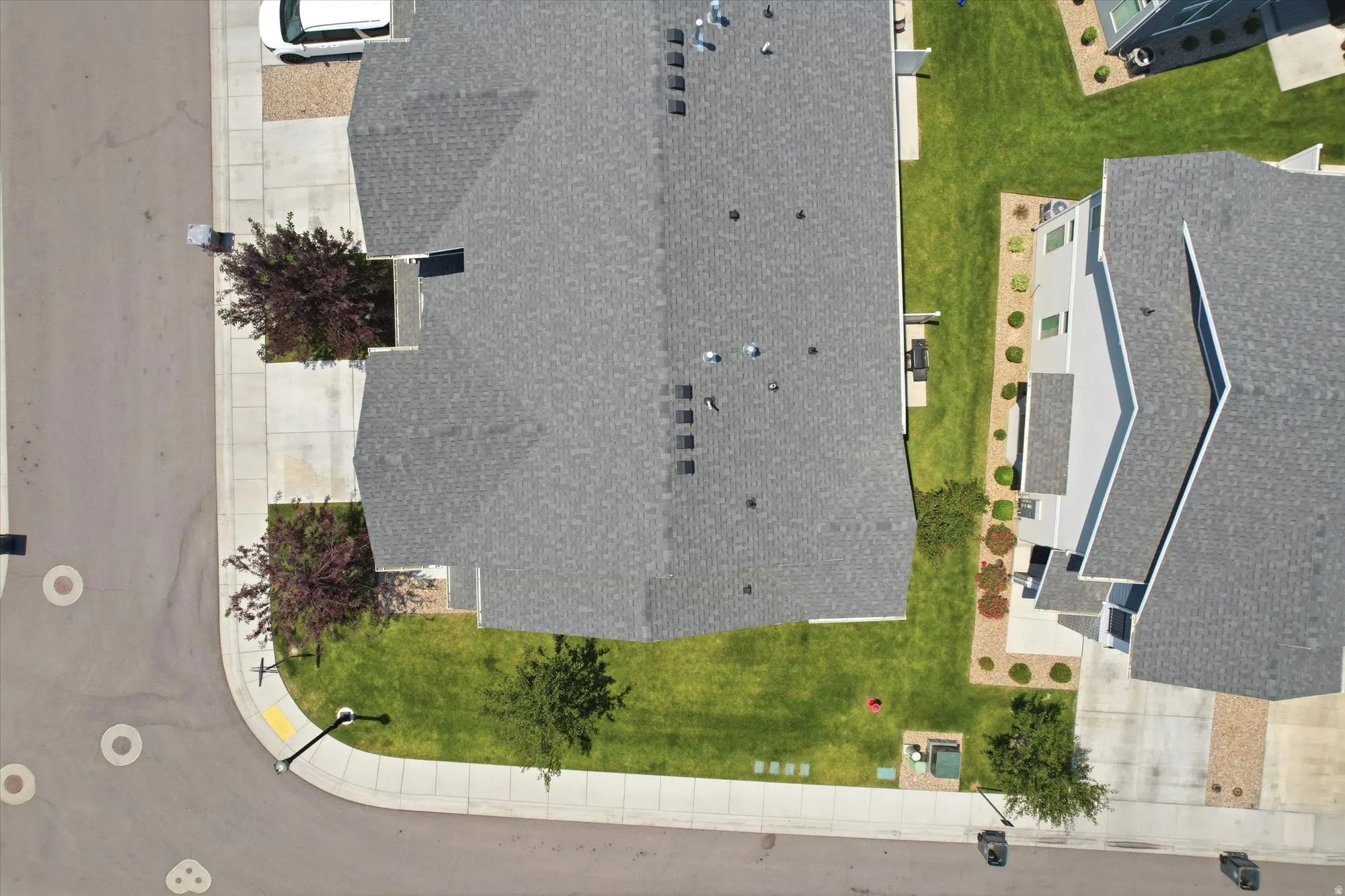 Aerial view showcasing a property with a gray shingle roof, green lawn, and mature trees