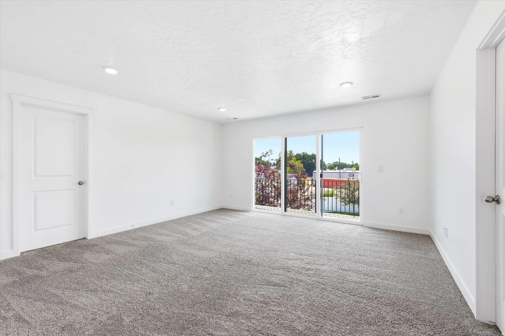 Spacious room with plush gray carpeting and white walls