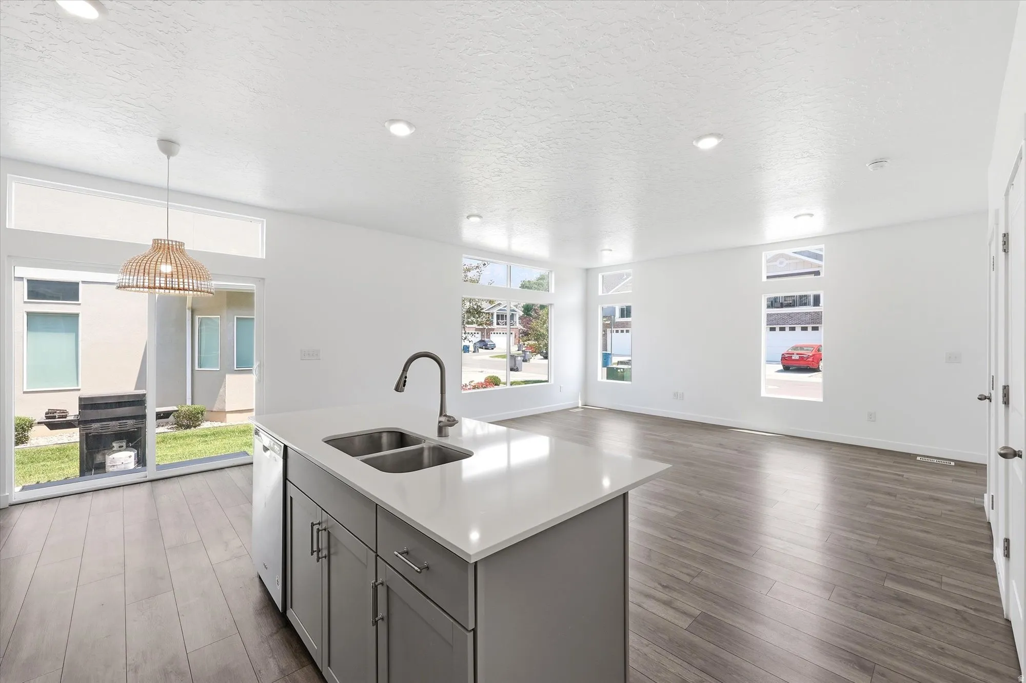 Modern kitchen island featuring a double-basin stainless steel sink, gooseneck faucet, light grey cabinetry with brushed nickel hardware, and a light-toned countertop