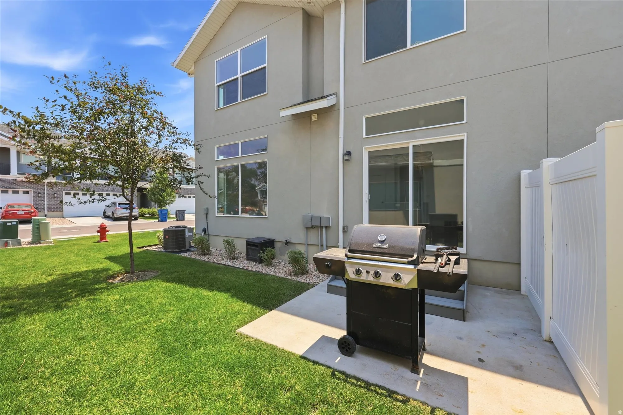 Rear exterior featuring stucco siding, multiple large windows, and a sliding glass door leading to a concrete patio