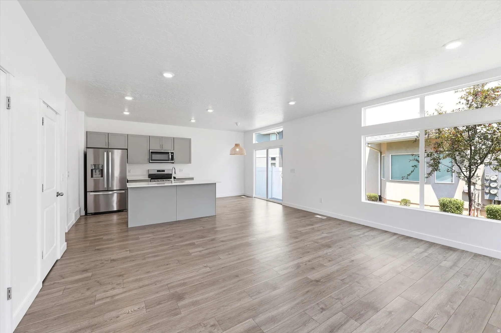 Open-concept living space featuring wood-finish flooring, recessed lighting, and large picture windows