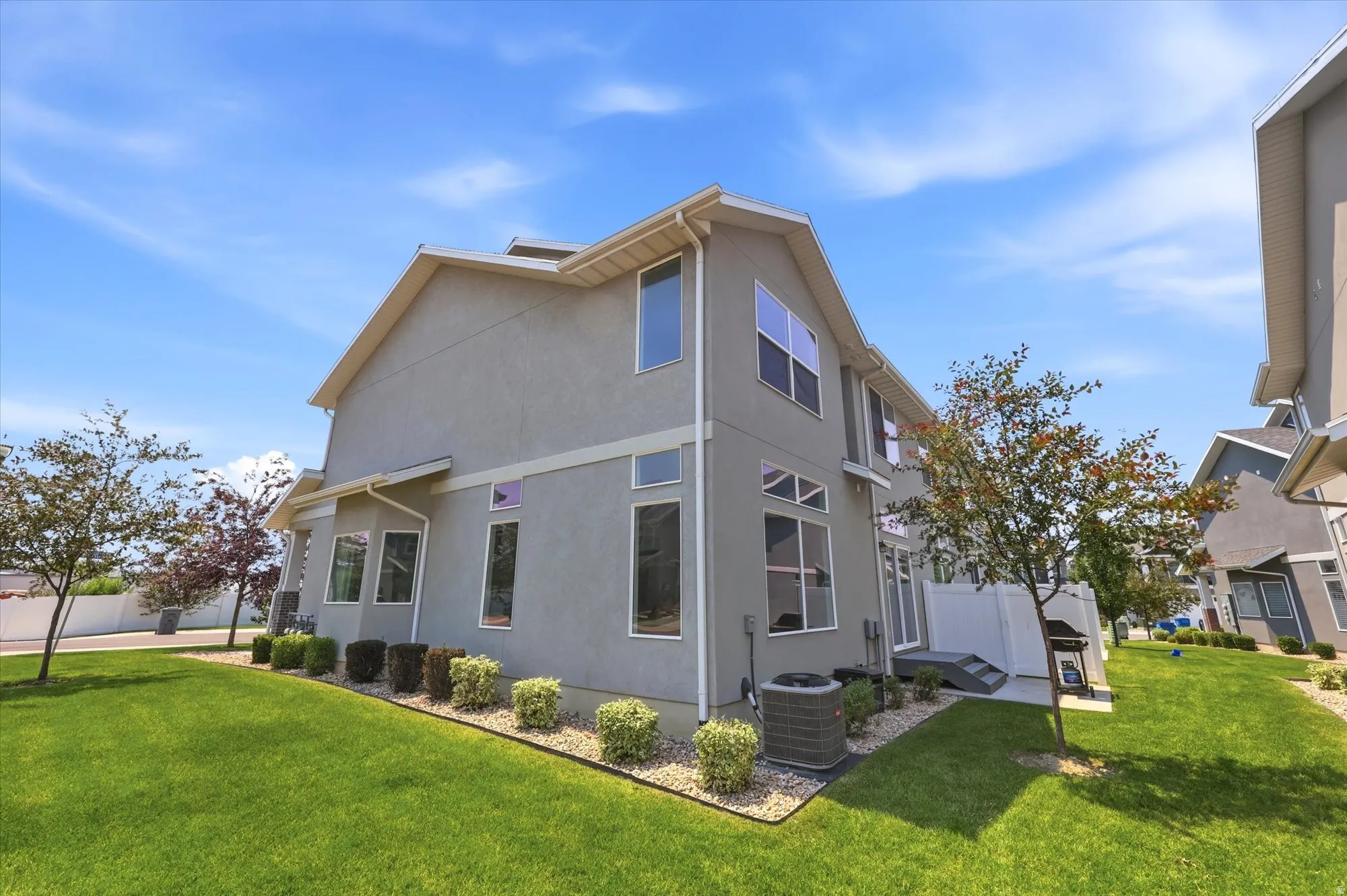 Stucco exterior featuring multiple windows, a side patio, and a well-maintained lawn