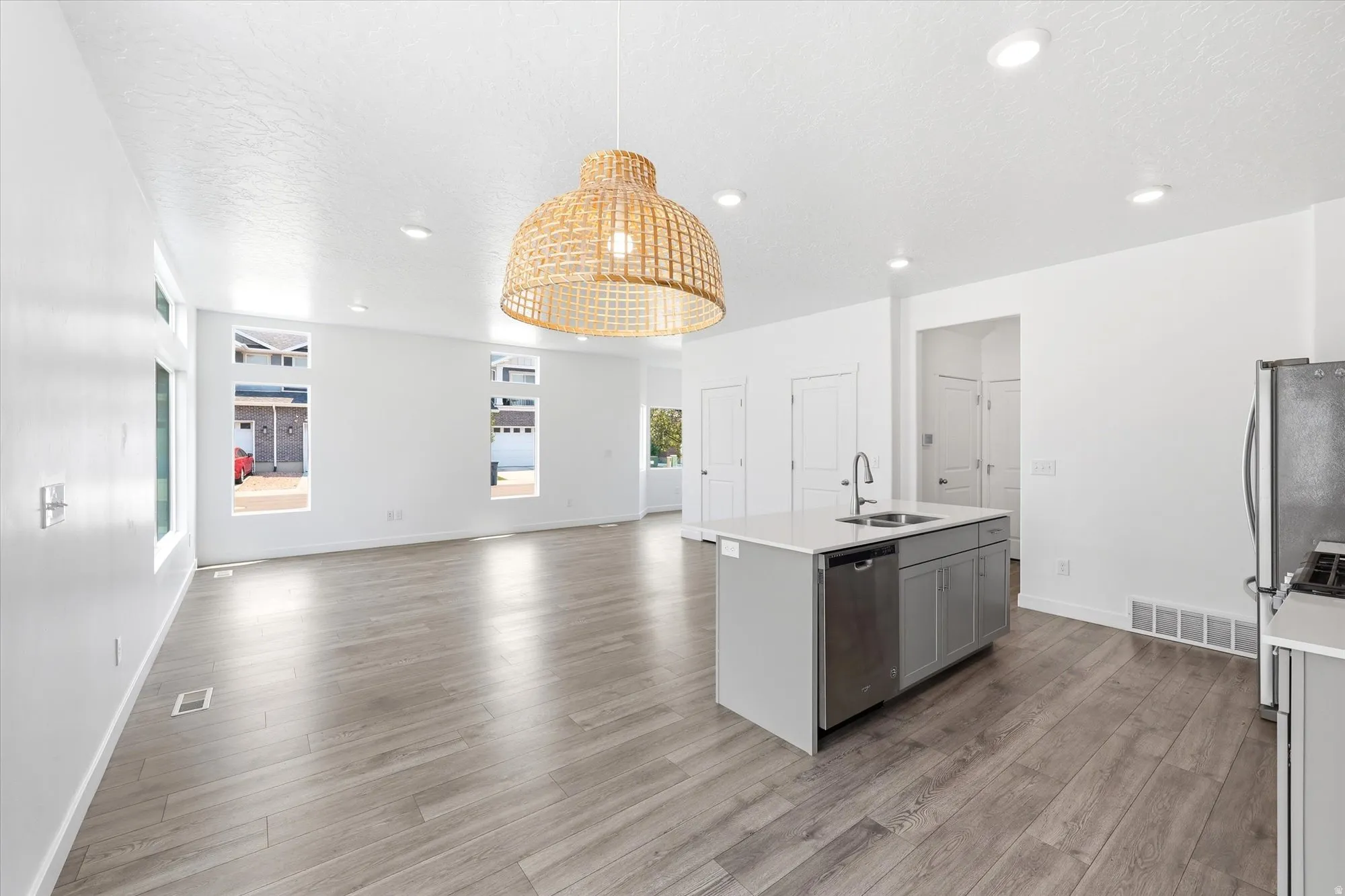 Open-concept living space featuring wood-finish flooring, recessed lighting, and a woven pendant light fixture
