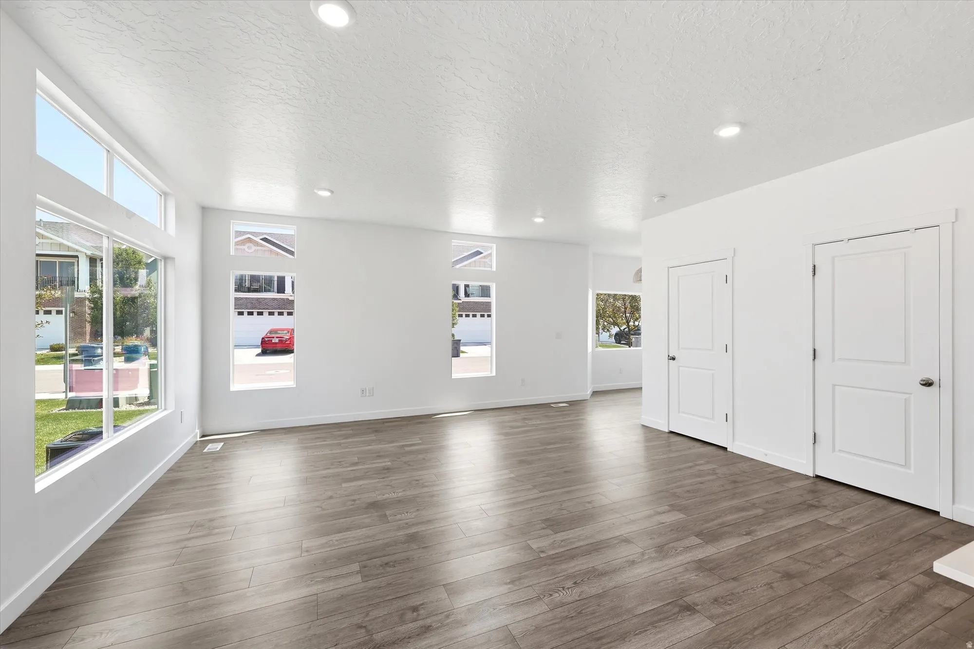 Expansive room featuring wood-finish flooring, recessed lighting, and white walls