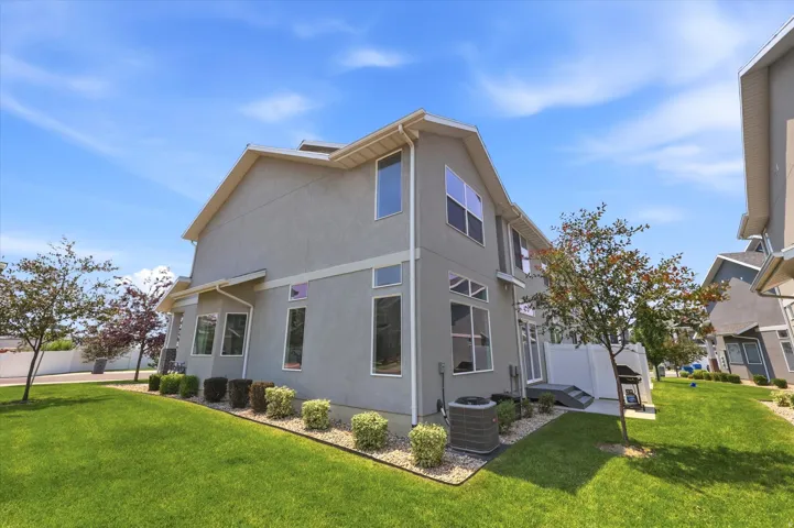 Stucco exterior featuring multiple windows, a side patio, and a well-maintained lawn