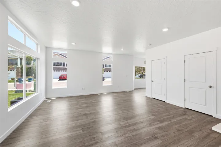 Expansive room featuring wood-finish flooring, recessed lighting, and white walls