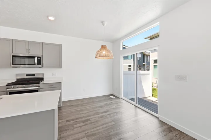 Modern kitchen and dining area featuring light gray cabinetry, stainless steel appliances, and white countertops
