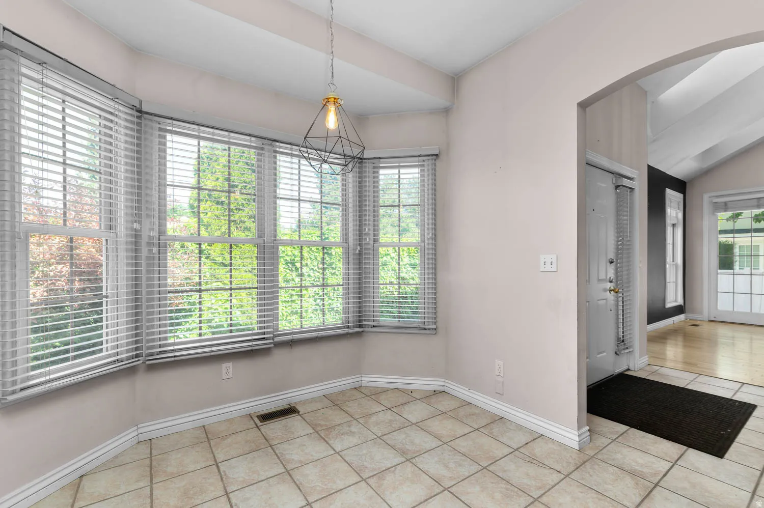 Bay window dining area featuring ceramic tile flooring, a geometric pendant light fixture, and vaulted ceilings
