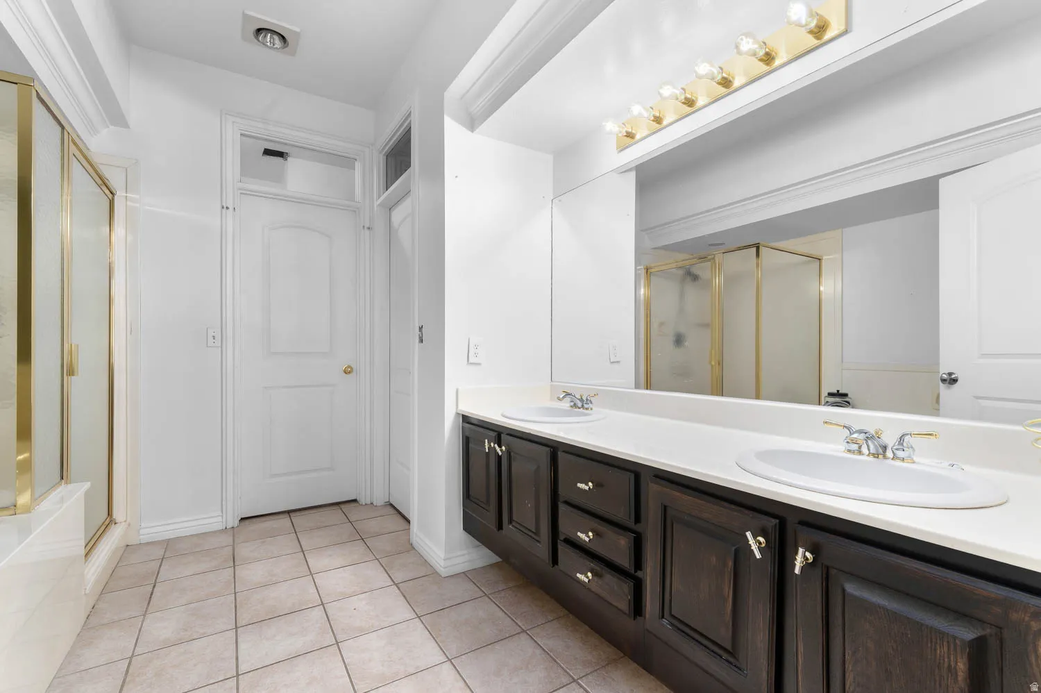Dual vanity with dark wood cabinetry, white countertops, and undermount sinks