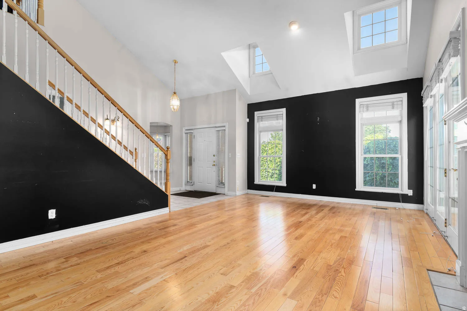 Open-concept living space featuring hardwood flooring, a vaulted ceiling, and multiple windows