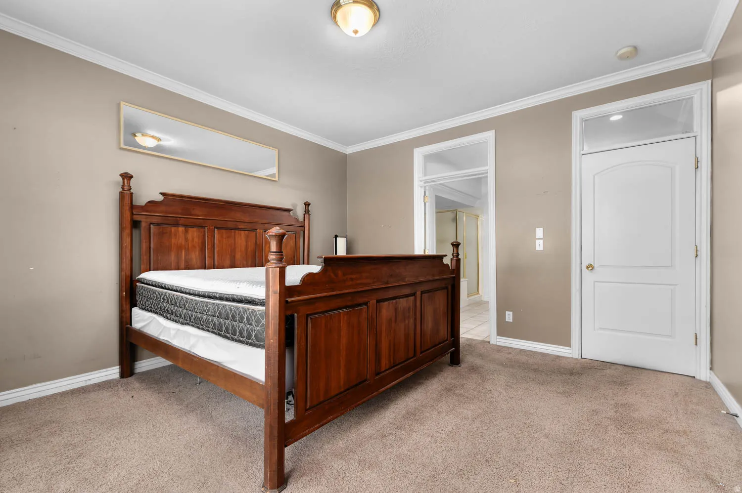 Carpeted room featuring crown molding, neutral wall tones, a solid panel interior door, and an arched doorframe leading to an adjoining space