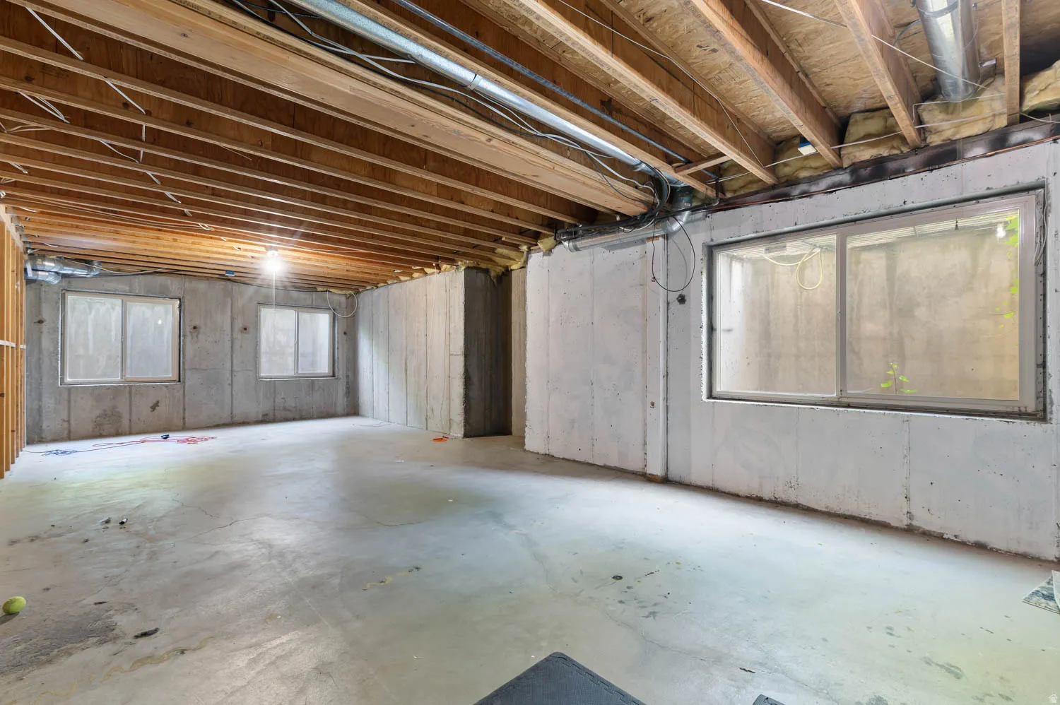 Unfinished lower level featuring exposed wood joists and concrete flooring
