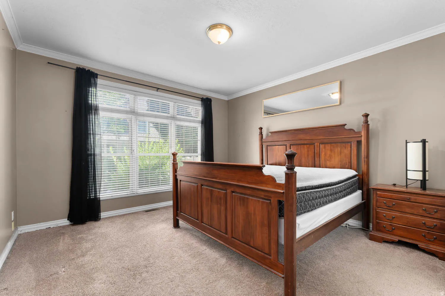 Carpeted room featuring a large window with blinds, crown molding, and a flush mount ceiling light