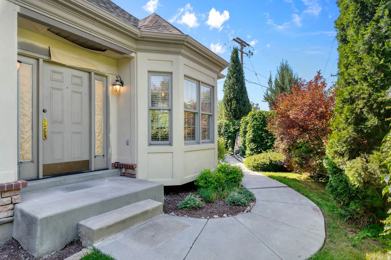 Inviting entryway featuring a paneled front door with sidelight windows, a decorative outdoor sconce, and a concrete stoop