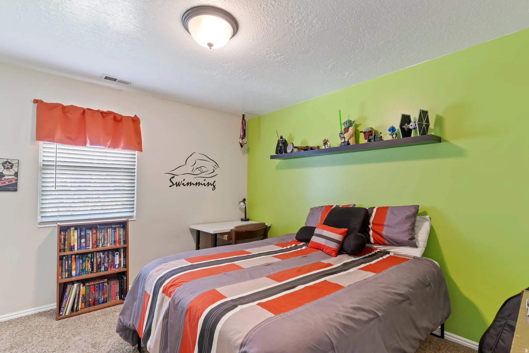 Bedroom featuring a textured ceiling, a window with blinds and a valance, and wall-mounted shelving